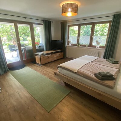 Ein helles, gemütliches Schlafzimmer im Bauernhof mit Doppelbett, Flachbild-TV und direktem Zugang zur sonnigen Terrasse.