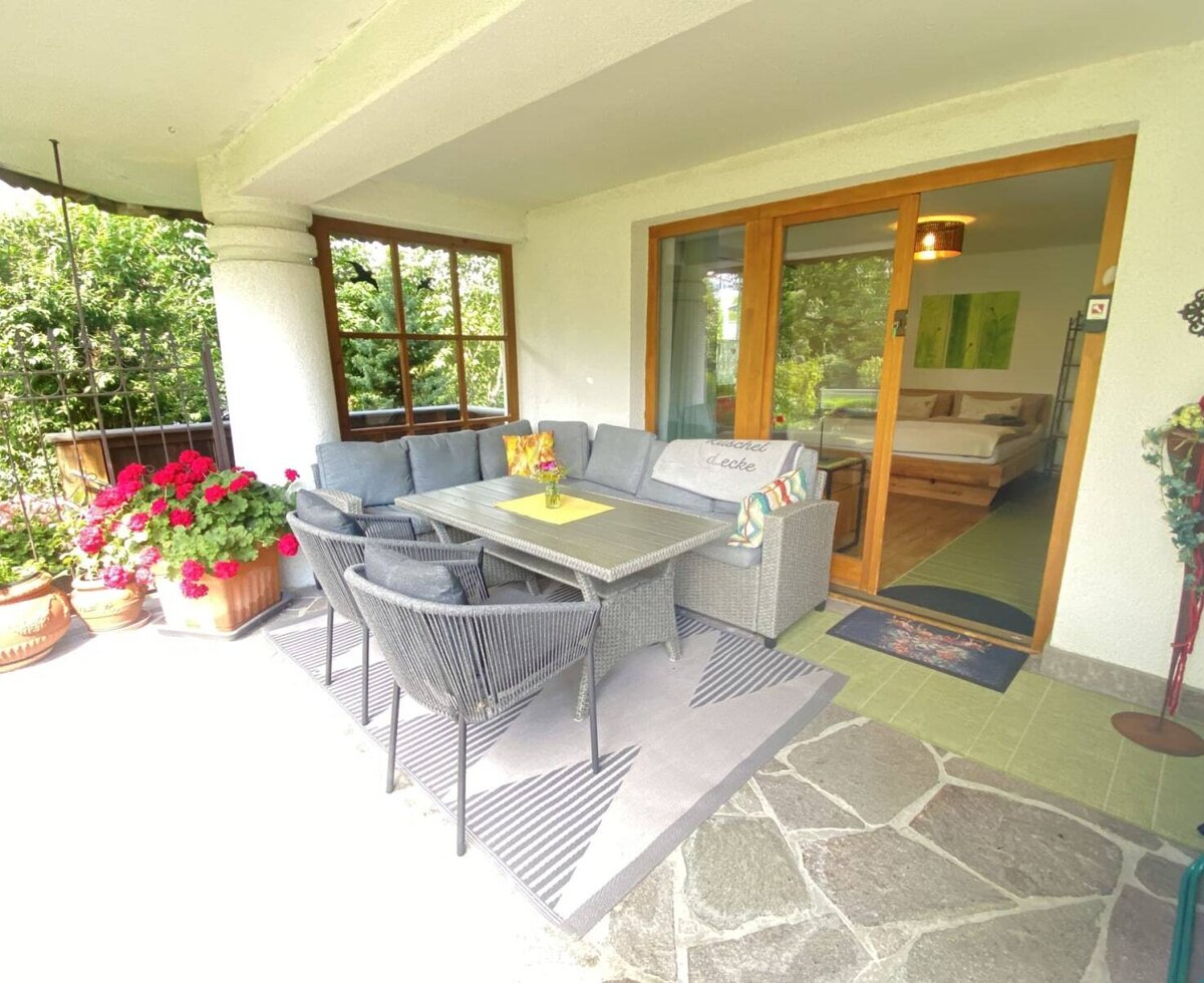 Die einladende Terrasse des Bauernhofs mit einer gemütlichen Sitzlandschaft, farbenfrohen Blumen und direktem Zugang zum Schlafzimmer.