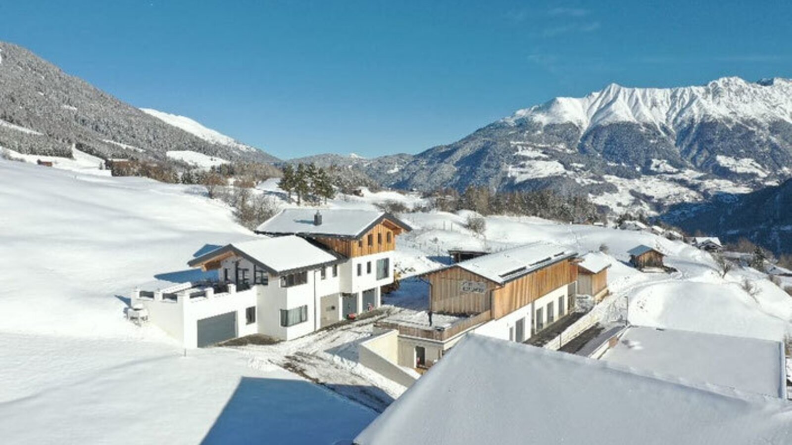 Die Ferienwohnungen in einer winterlichen Berglandschaft, umgeben von schneebedeckten Hängen und Bergen.