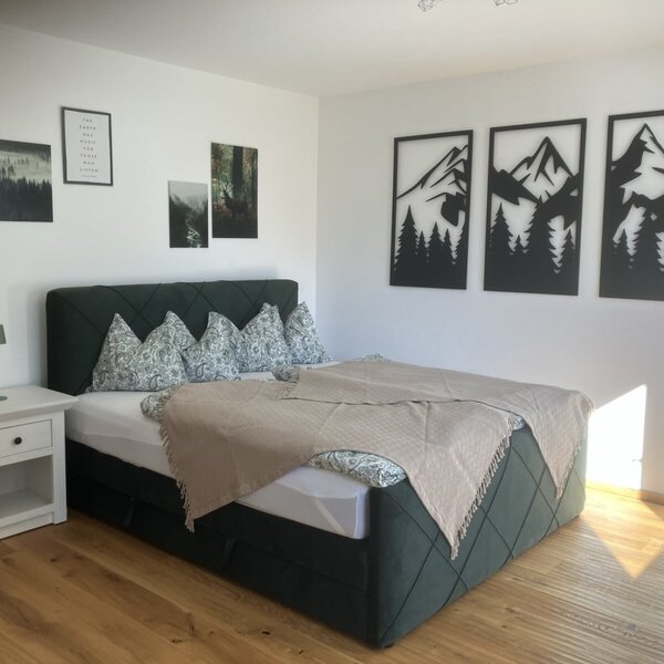 Ein einladendes Schlafzimmer im Appartement mit einem gemütlichen Doppelbett, stilvoller Wanddeko und warmem Parkettboden.