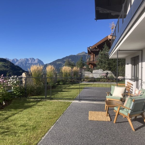 Die sonnige Terrasse des Bed and Breakfasts bietet einladende Sitzgelegenheiten, einen gepflegten Rasen und einen herrlichen Blick auf die umliegenden Berge.