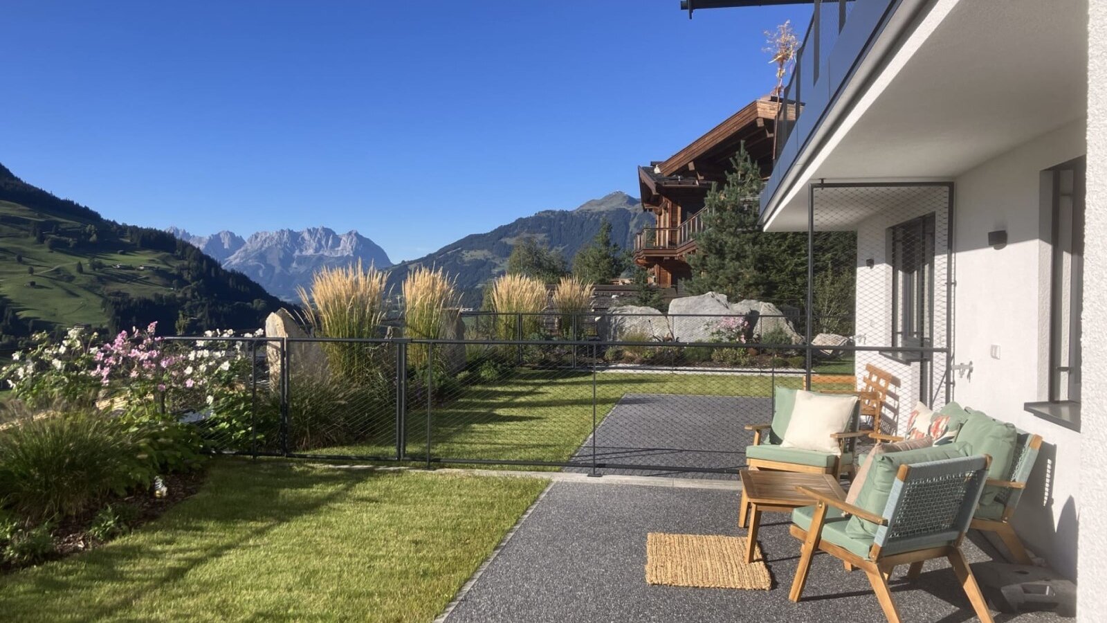 Die sonnige Terrasse des Bed and Breakfasts bietet einladende Sitzgelegenheiten, einen gepflegten Rasen und einen herrlichen Blick auf die umliegenden Berge.