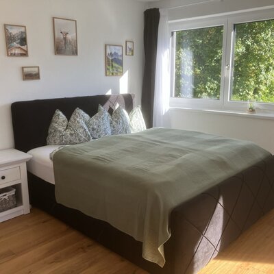 Ein helles und einladendes Doppelzimmer im Bed and Breakfast mit einem gemütlichen Doppelbett, warmem Holzboden und einem großen Fenster mit Blick ins Grüne.