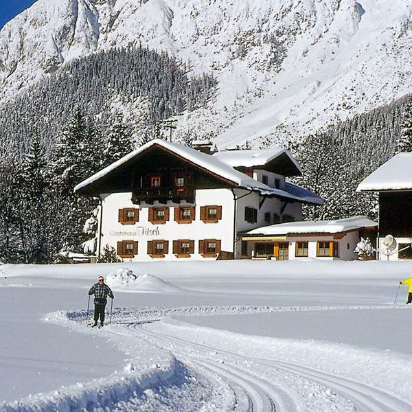 Der Bauernhof in winterlicher Umgebung mit direkter Langlaufloipe und Blick auf die Tiroler Bergwelt.