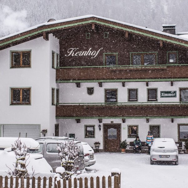 Die Außenansicht des Bauernhofs Kernhof, im Winter mit Schnee bedeckt und mit Hinweisschild für Zimmer.