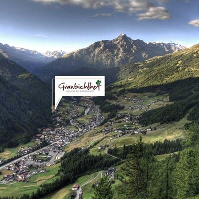 Ein Panoramablick auf das Tal mit der Ortschaft und den umliegenden Bergen, der die Lage des Bauernhofs Granbichlhof zeigt.