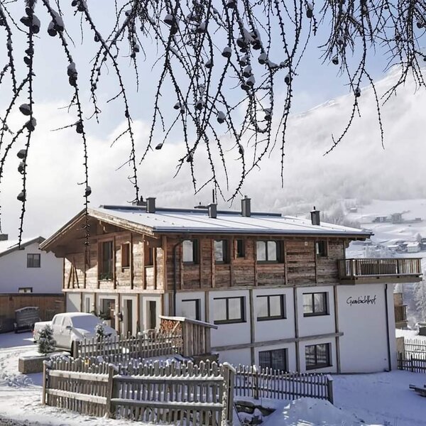 Außenansicht des schneebedeckten Bauernhofs Gundlachhof mit Bergblick.