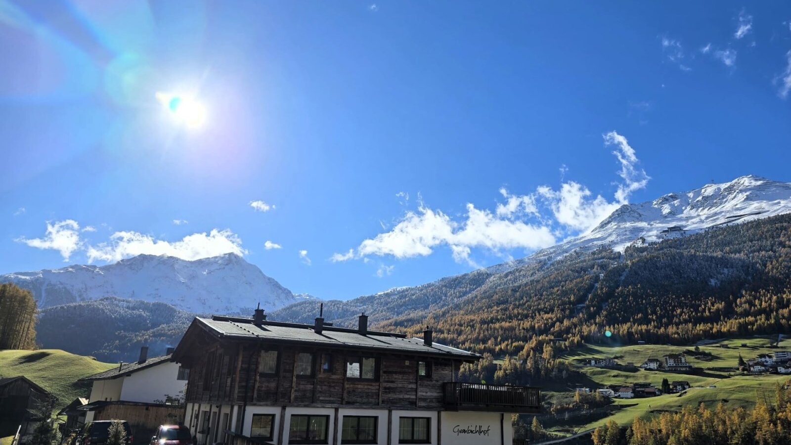 Der Bauernhof mit Blick auf die schneebedeckten Berge und das Tal unter blauem Himmel.