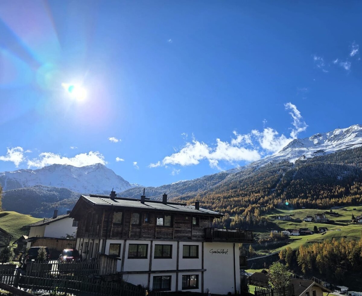 Der Bauernhof mit Blick auf die schneebedeckten Berge und das Tal unter blauem Himmel.