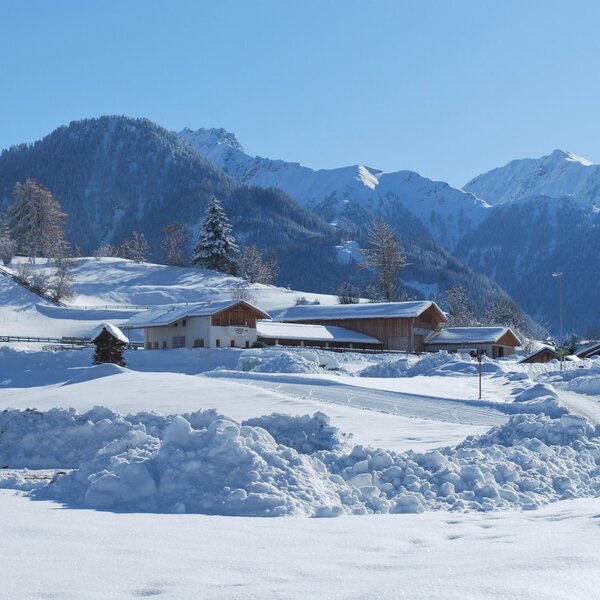 Der Darrehof Bauernhof in einer schneebedeckten Winterlandschaft mit Bergen im Hintergrund.