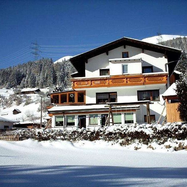 Der Bauernhof von außen, mit Balkon und Wintergarten, umgeben von Schnee.