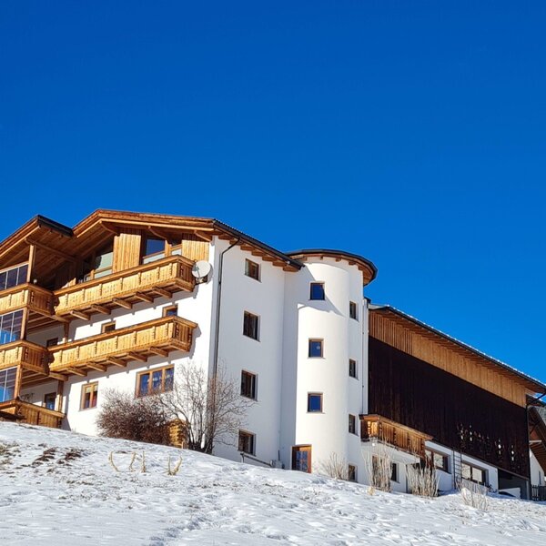 Der Bauernhof im Winter, mit weißer Fassade, Holzverkleidung und Balkonen, auf einem schneebedeckten Hügel. Der Bauernhof im Winter, mit weißer Fassade, Holzverkleidung und Balkonen, auf einem schneebedeckten Hügel.