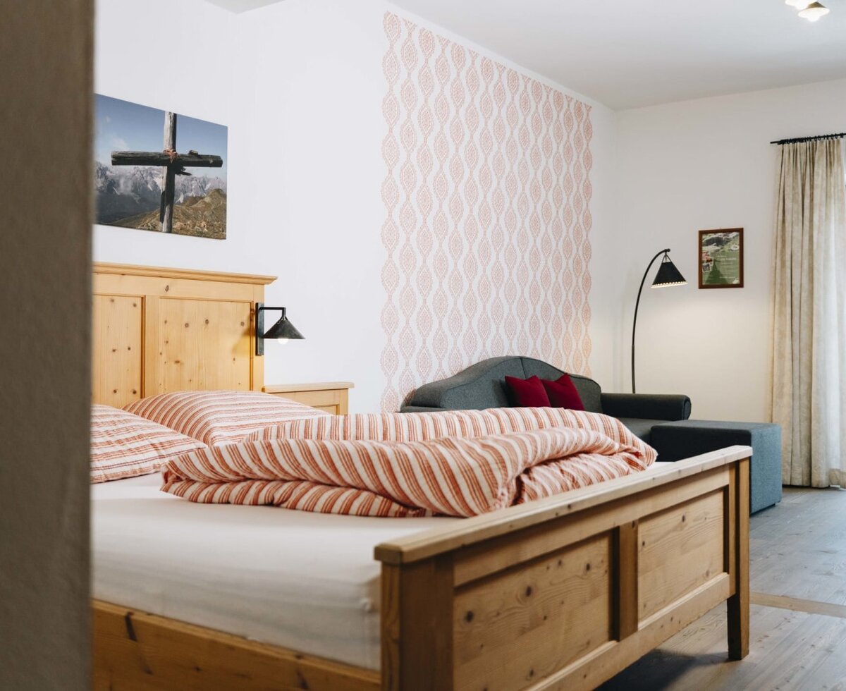 Schlafzimmer im Bauernhof mit Holzbett, Sofa und Zugang zum Balkon.
