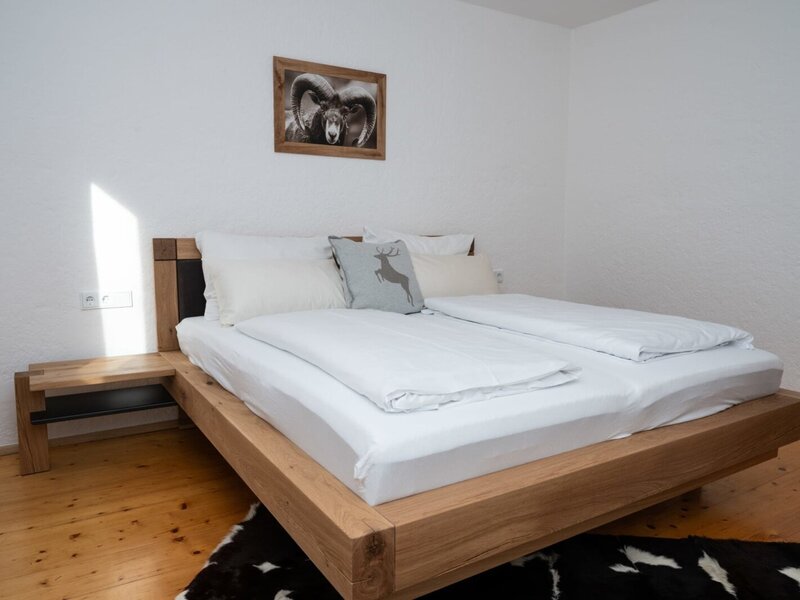 Schlafzimmer im Apartment mit einem Doppelbett aus Holz, integriertem Nachttisch und Holzboden.