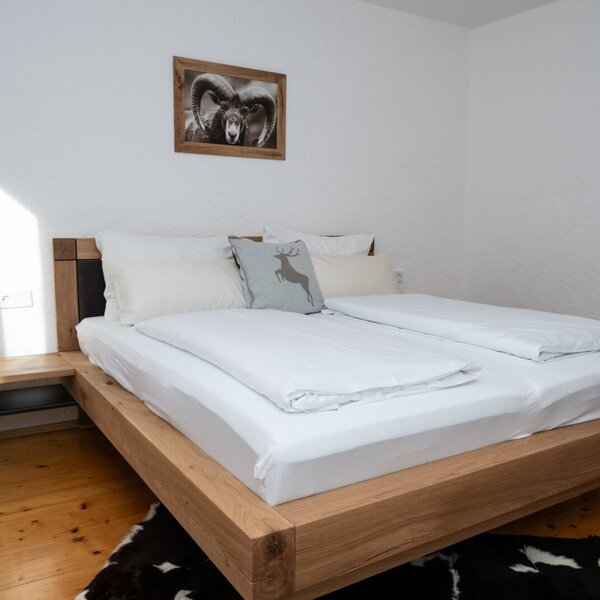 Schlafzimmer im Apartment mit einem Doppelbett aus Holz, integriertem Nachttisch und Holzboden.
