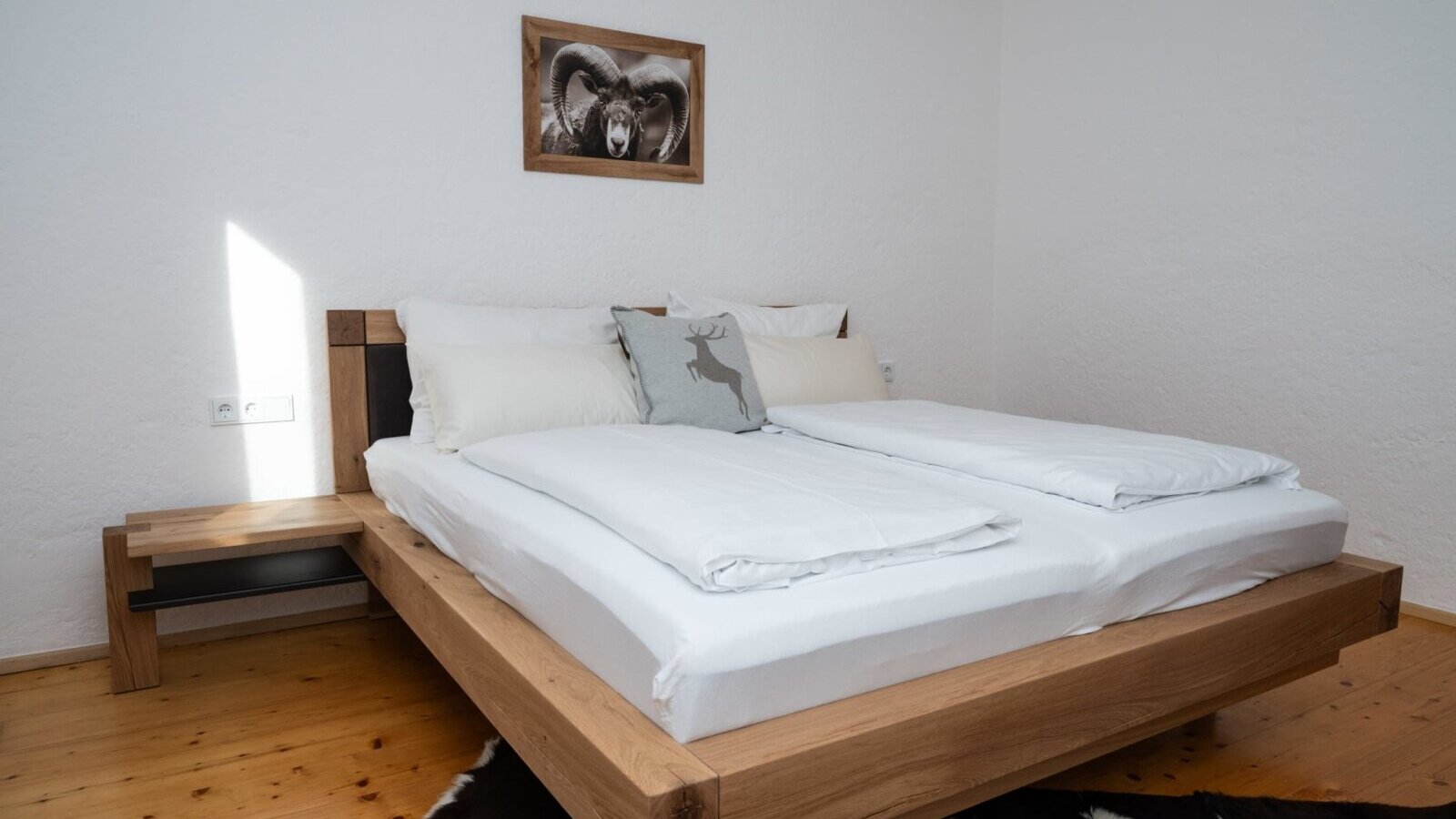 Schlafzimmer im Apartment mit einem Doppelbett aus Holz, integriertem Nachttisch und Holzboden.