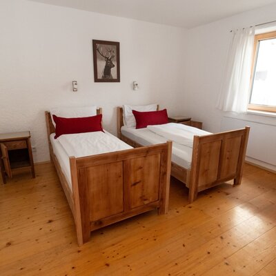 Schlafzimmer im Bed and Breakfast mit zwei Einzelbetten, Holzböden und einem Fenster.