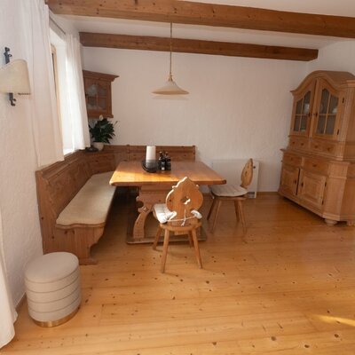 Der Essbereich im Apartment mit einem Holztisch, Eckbank und traditionellen Holzstühlen unter sichtbaren Deckenbalken.