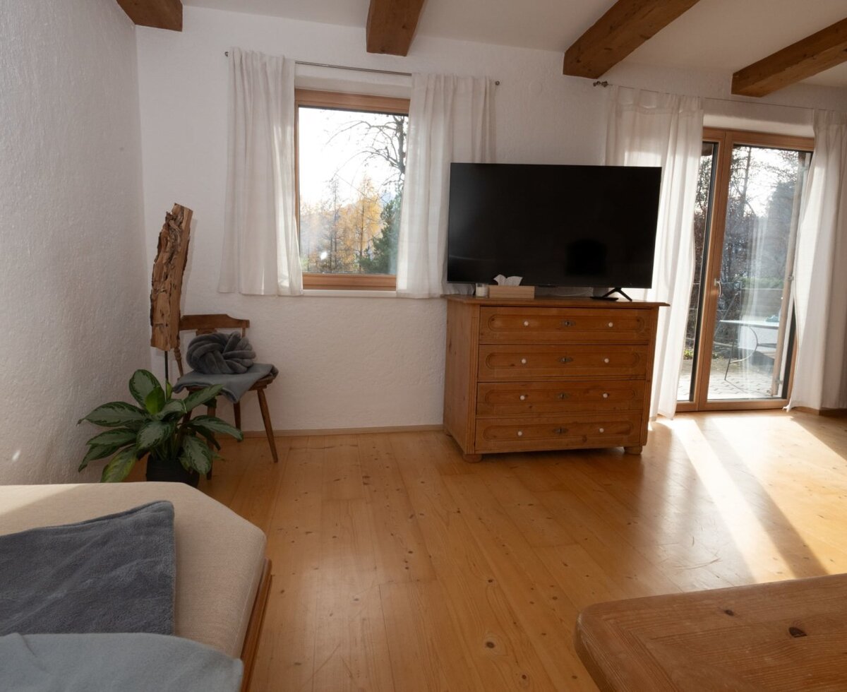 Wohnbereich des Apartments mit TV, Holzkommode und direktem Zugang zur Terrasse.