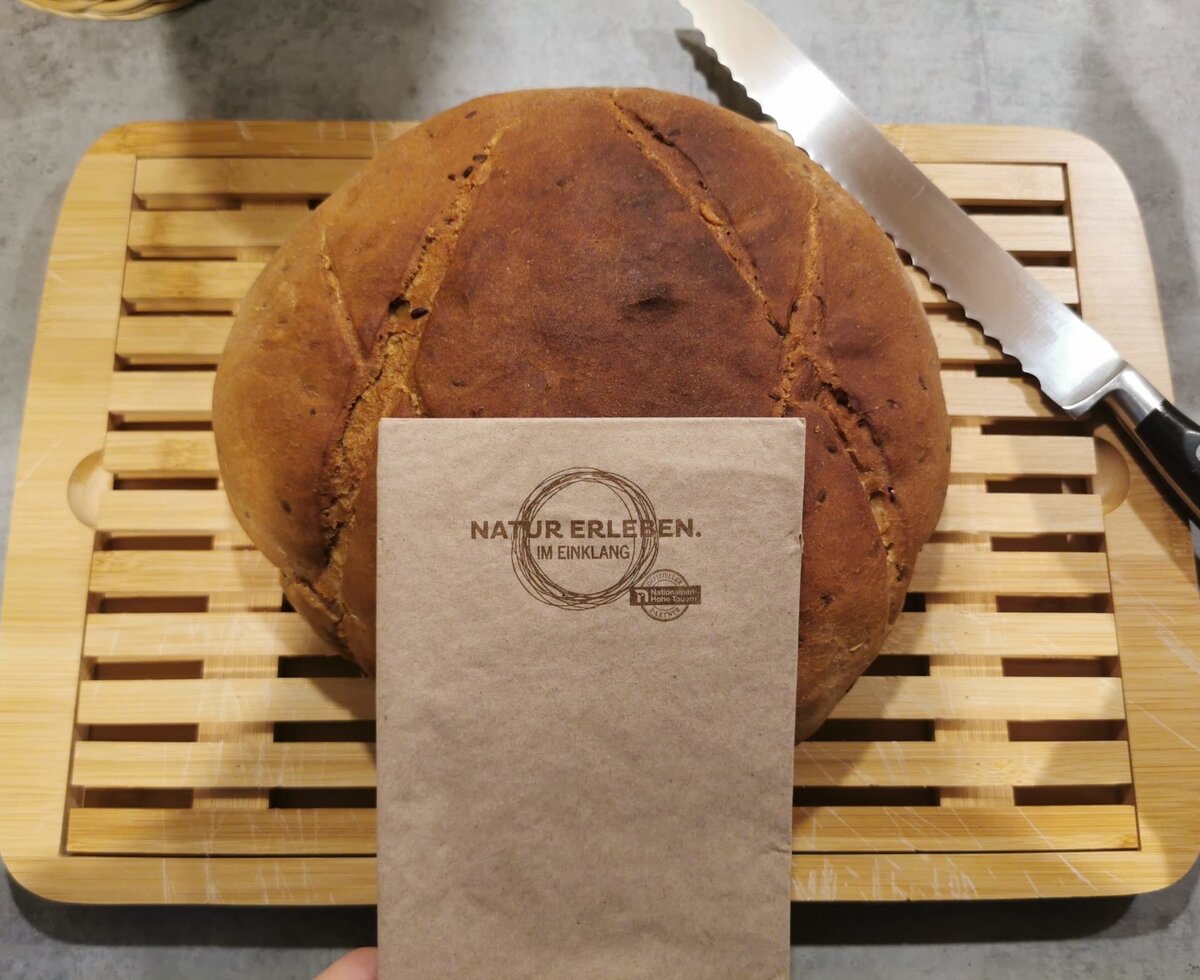 Frisch gebackenes Brot vom Bauernhof auf einem Holzschneidebrett mit Brotmesser.