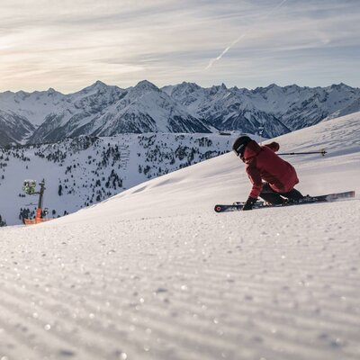 Ein Skifahrer auf einer präparierten Piste in den Zillertaler Alpen, der Bergregion, die den Bauernhof umgibt.