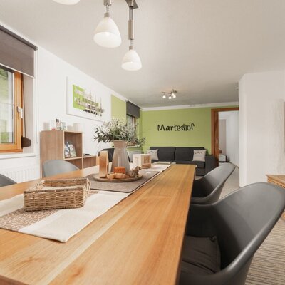 Der Essbereich im Bauernhof verfügt über einen langen Holztisch mit Stühlen und geht in den Wohnbereich mit Sofa und Fernseher über.