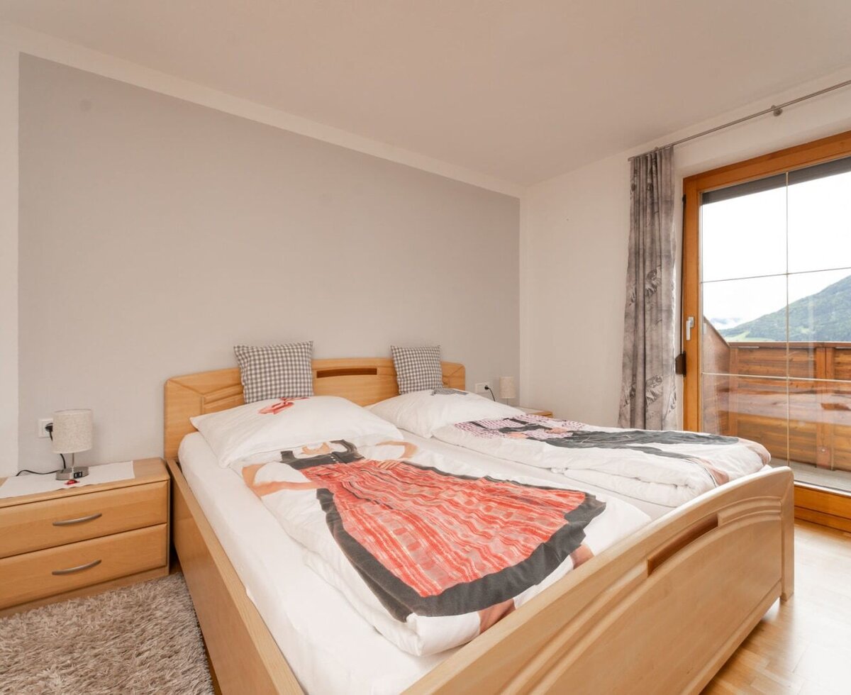 Schlafzimmer mit zwei Einzelbetten im Bauernhof, mit zwei Nachttischen und Balkonzugang mit Bergblick.