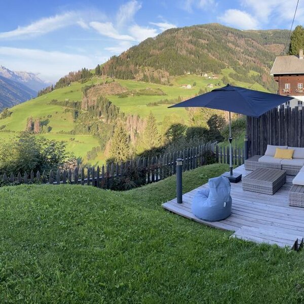 Terrasse mit Lounge-Möbeln und Bergblick am Bauernhof.