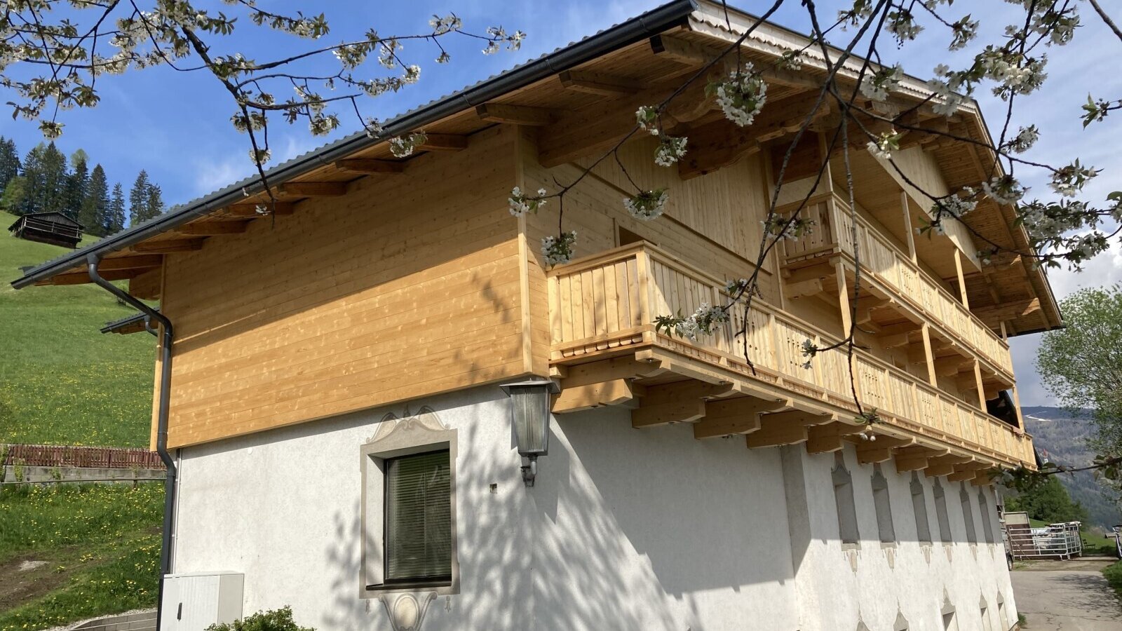 Außenansicht des Bauernhofs mit Holzfassade und mehreren Balkonen.