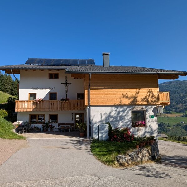 Der Bauernhof mit Balkonen und einer Terrasse mit Blick auf die Berge.