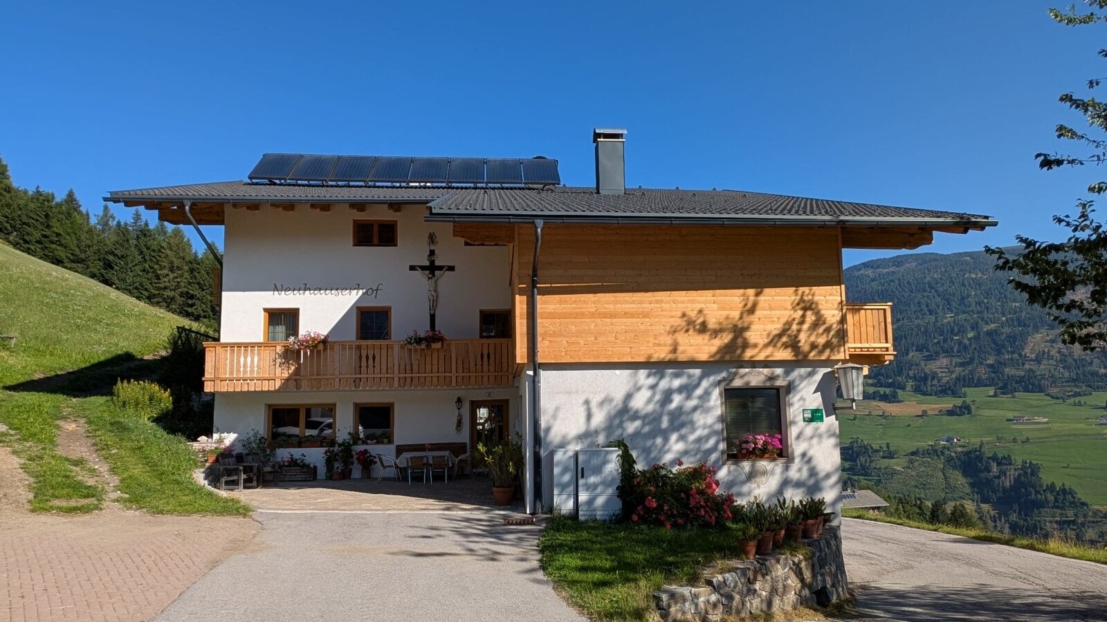 Der Bauernhof mit Balkonen und einer Terrasse mit Blick auf die Berge.