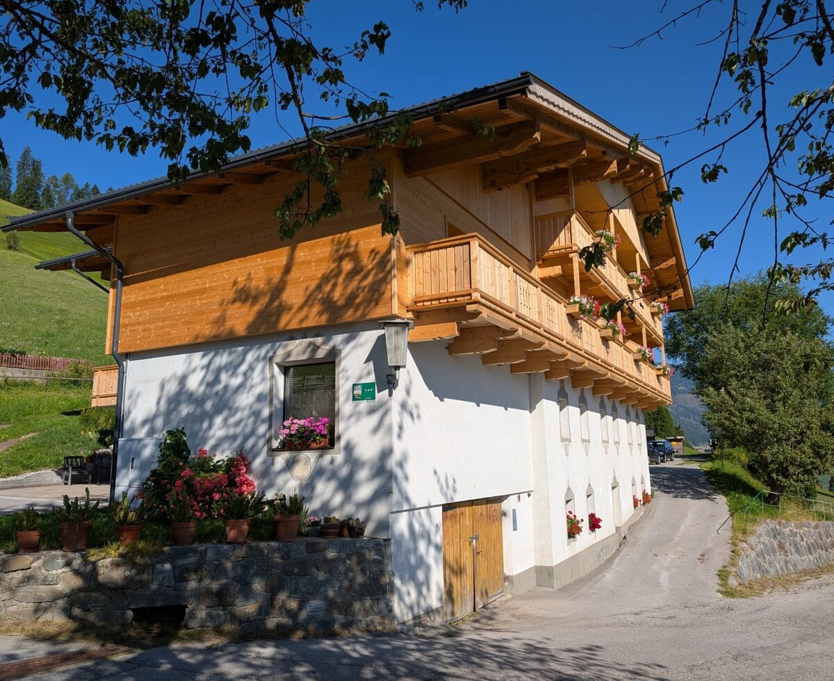 Der Bauernhof von außen, mit Holzbalkonen und Blumenkästen.