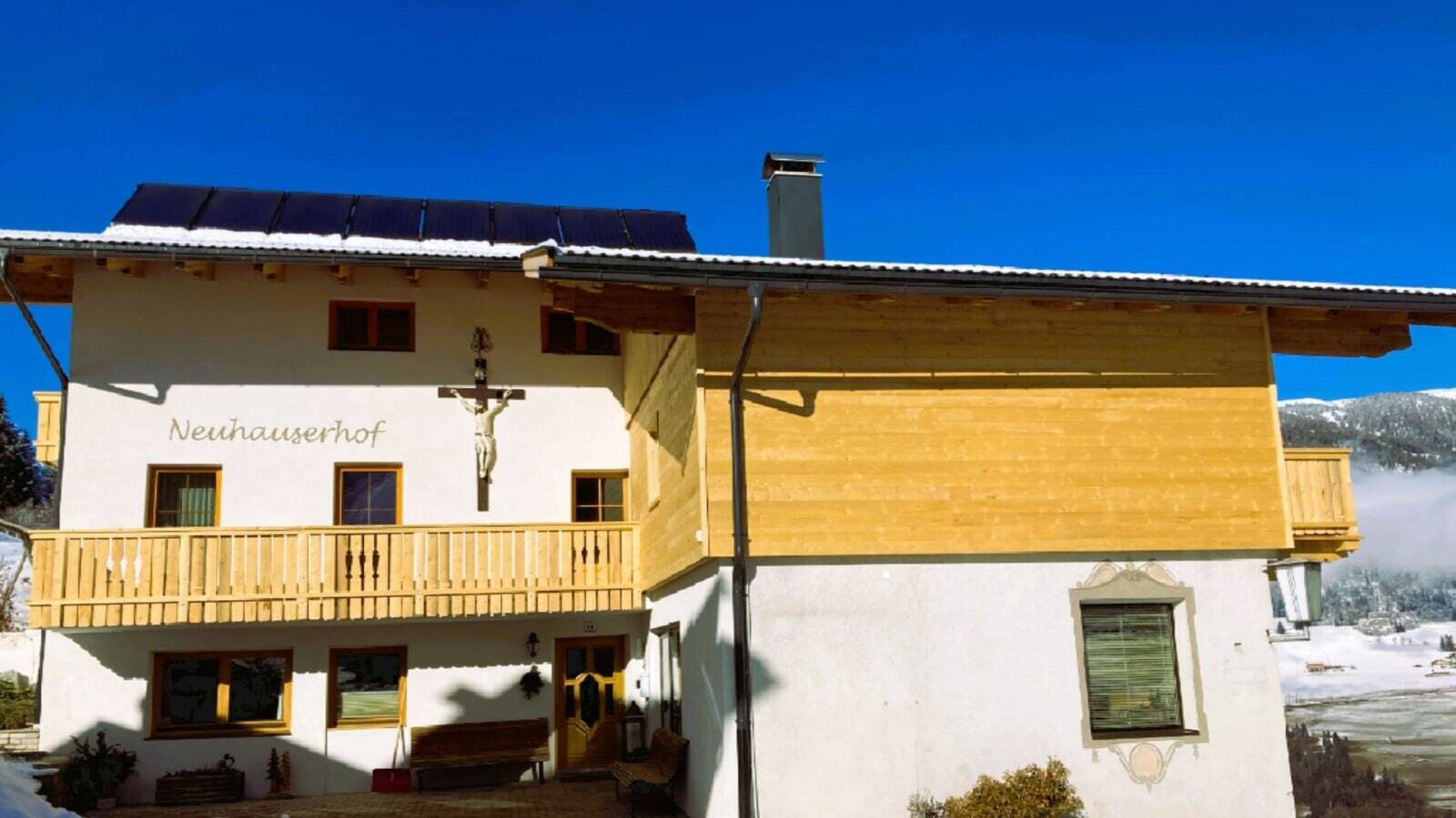 Außenansicht des Bauernhofs Neuhauserhof mit Balkonen und Solarpaneelen auf dem Dach.