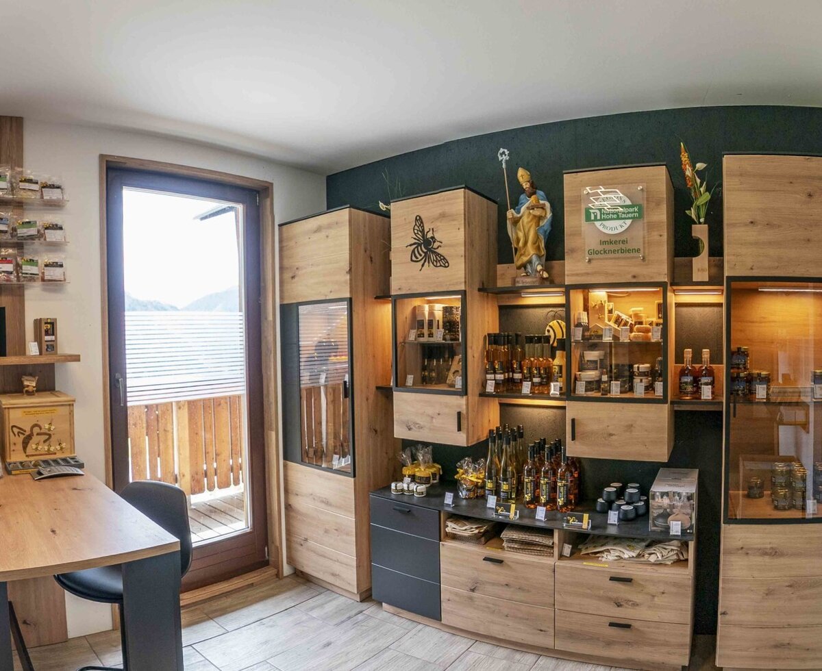 Verkaufsbereich im Bauernhof mit Holzregalen, lokalen Produkten und Zugang zum Balkon.