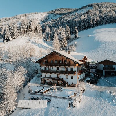 Der Bauernhof in einer verschneiten Berglandschaft mit Kinderspielplatz.
