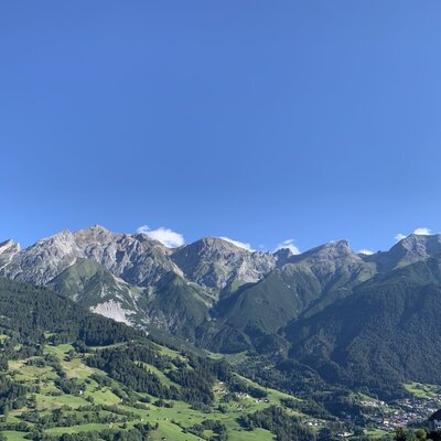 Blick auf die Berge, bewaldete Hänge und ein Tal mit einem Dorf vom Bauernhof aus.