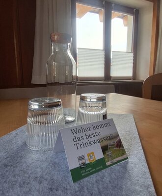 Frisches Trinkwasser in einer Karaffe mit Gläsern auf dem Tisch für Gäste der Ap­par­te­ments.