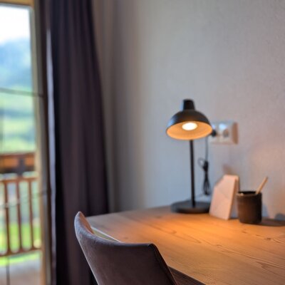 Schreibtisch im Bauernhof mit Lampe und Stuhl, mit Zugang zum Balkon und Bergblick.