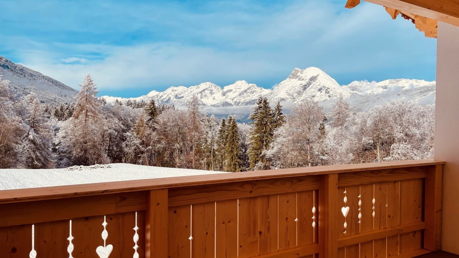 Malerischer Ausblick auf verschneite Wälder und die winterliche Bergkulisse.