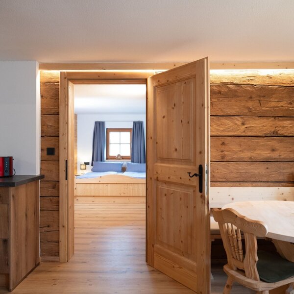 Küchen- und Essbereich des Ap­par­te­ments mit Holzeinrichtung und Zugang zu einem Schlafzimmer.