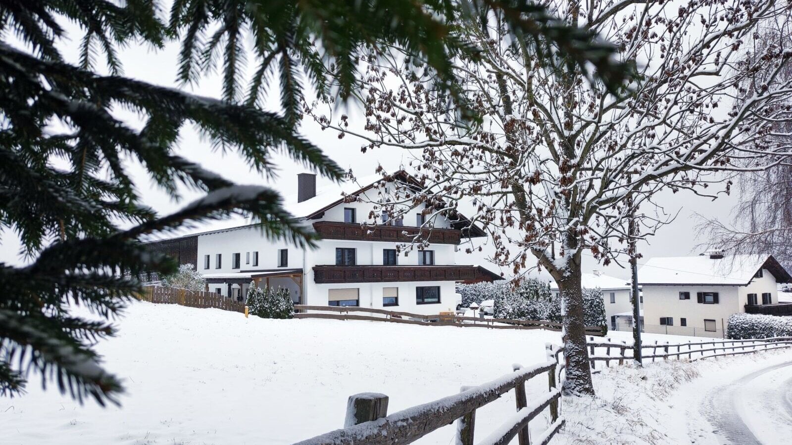 Außenansicht des Bauernhofs im Winter, mit Schnee bedeckter Landschaft und einem Holzzaun.
