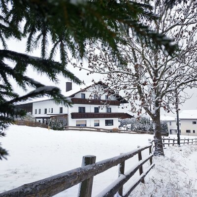 Außenansicht des Bauernhofs im Winter, mit Schnee bedeckter Landschaft und einem Holzzaun.