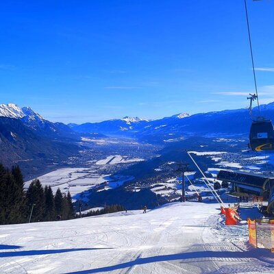 Skipiste oder Oberperfer Bergbahnen mit Gondelbahn und Panoramablick auf das schneebedeckte Tal und die umliegenden Berge.