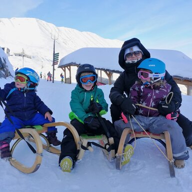 Rodelspaß für die ganze Familie in der verschneiten Berglandschaft rund um den Bauernhof.