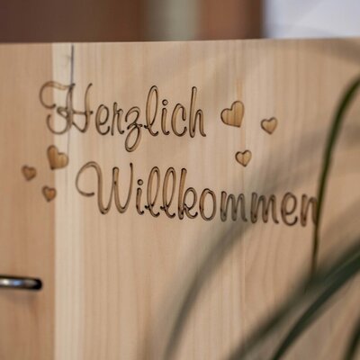 Holzschild mit der Gravur "Herzlich Willkommen" auf dem Bauernhof.