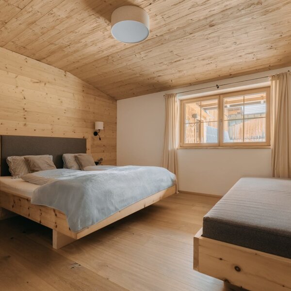 Schlafzimmer der Ferienwohnung mit Doppelbett, Tagesbett und Holzeinrichtung.