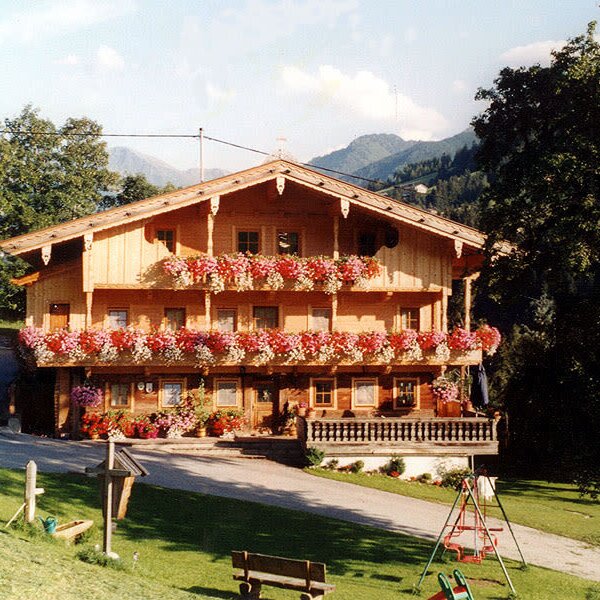Der Bauernhof mit Holzfassade und blumengeschmückten Balkonen bietet einen Kinderspielplatz im Grünen.