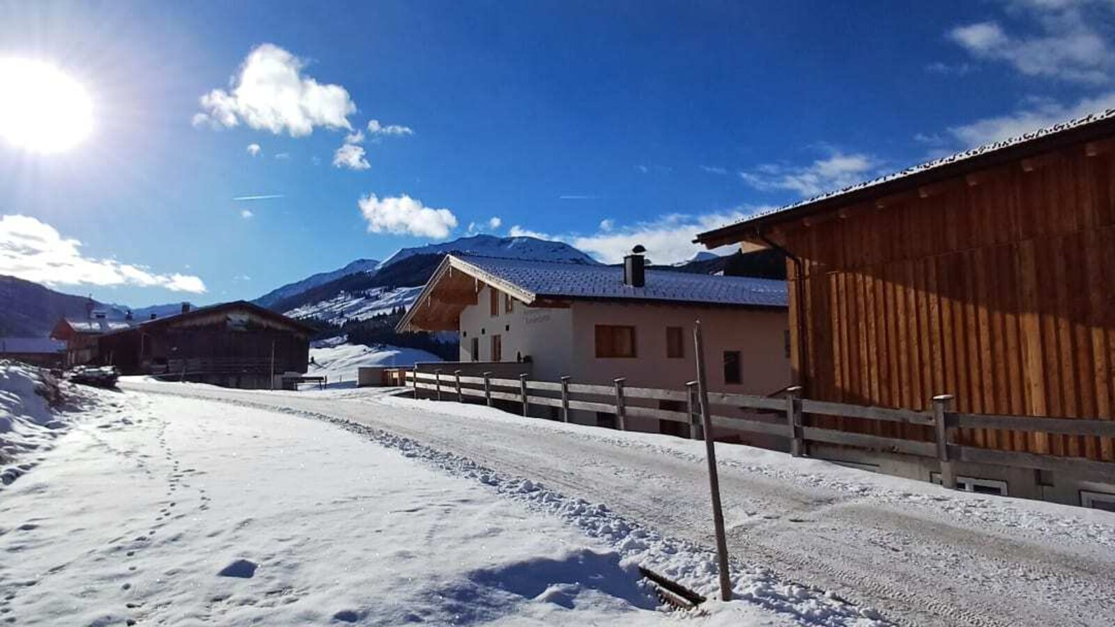 Der idyllische Bauernhof inmitten einer verschneiten Winterlandschaft unter strahlend blauem Himmel.