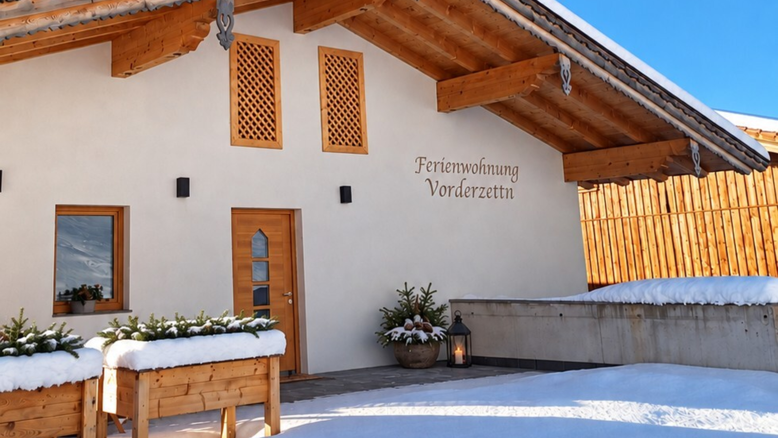 Der einladende, schneebedeckte Eingangsbereich des Bauernhofs unter strahlend blauem Himmel.