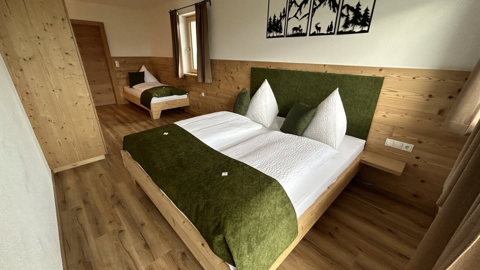 Schlafzimmer im Bauernhof mit einem Doppelbett und einem Einzelbett, eingerichtet mit Holzmöbeln und Wandpaneelen.